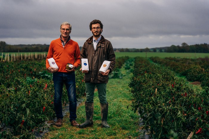 Christophe et Jules Gautier posant dans un champ avec leurs produits dans les mains.