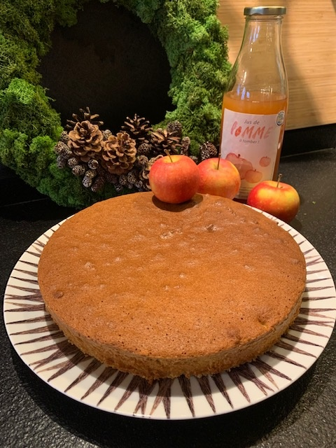 Gâteau posé dans un plat avec trois pommes à droite et une bouteille de jus de pomme logoté © du Centre