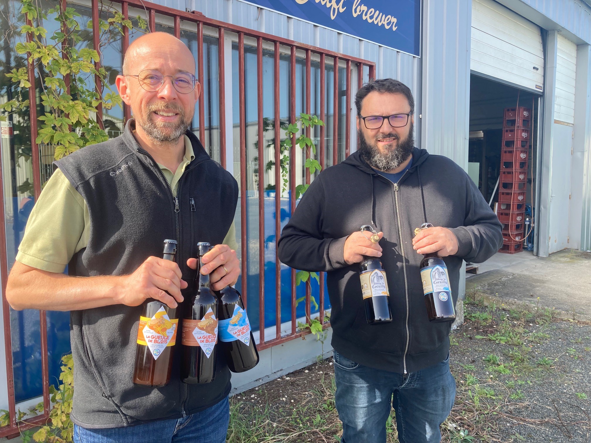 Guillaume Leclercq et son salarié devant la brasserie Guillaume avec deux bières en bouteille dans les mains